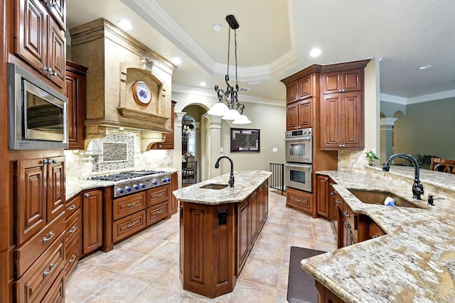 4503 Summits Edge Ln, Katy, TX 77494 - kitchen with stainless steel appliances, decorative columns, a center island with sink, tasteful backsplash, and light stone countertops