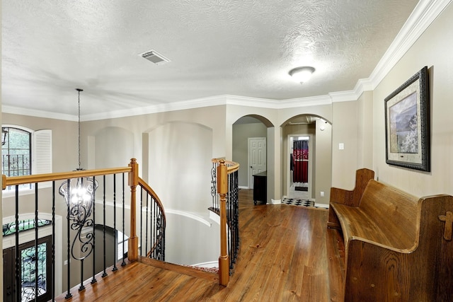 4503 Summits Edge Ln, Katy, TX 77494 - corridor featuring an upstairs landing, wood finished floors, a textured ceiling, arched walkways, and ornamental molding