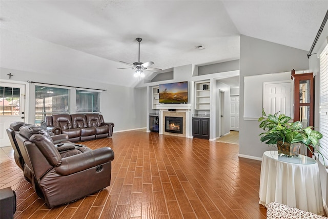 5810 Dixie Ln, Baytown, TX 77523 - living room featuring vaulted ceiling, ceiling fan, wood finished floors, a glass covered fireplace, and built in features