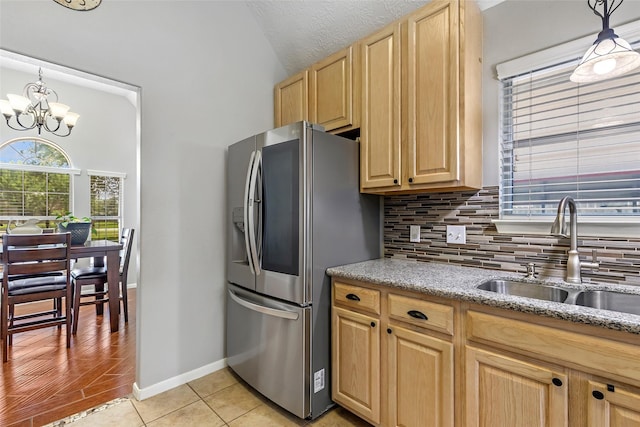 5810 Dixie Ln, Baytown, TX 77523 - kitchen featuring stainless steel fridge, tasteful backsplash, vaulted ceiling, light stone counters, and light brown cabinetry