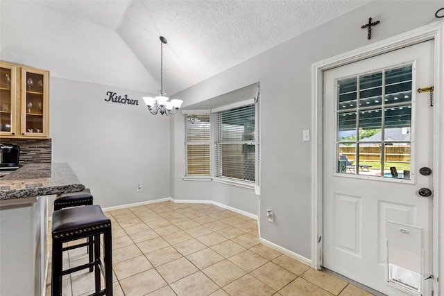5810 Dixie Ln, Baytown, TX 77523 - kitchen with light tile patterned floors, lofted ceiling, a chandelier, tasteful backsplash, and a textured ceiling