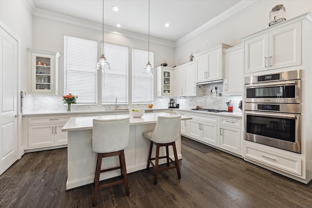 6019 Matthew Oaks Pl, Houston, TX 77007 - kitchen with double oven, light countertops, white cabinets, glass insert cabinets, and ornamental molding