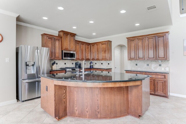 2215 Dali Ln, Missouri City, TX 77459 - kitchen with appliances with stainless steel finishes, a sink, an island with sink, arched walkways, and dark stone countertops