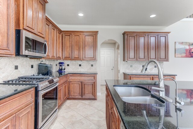 2215 Dali Ln, Missouri City, TX 77459 - kitchen featuring stainless steel appliances, a sink, arched walkways, dark stone counters, and recessed lighting