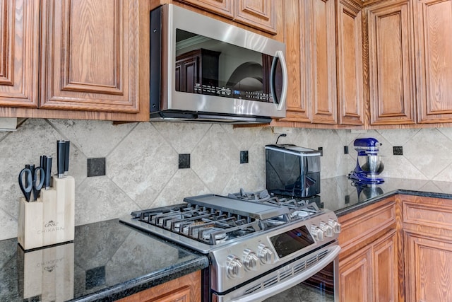 2215 Dali Ln, Missouri City, TX 77459 - kitchen with stainless steel appliances, decorative backsplash, brown cabinetry, and dark stone countertops