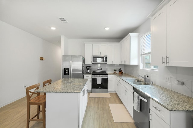 16910 Elm Grove Rd, Conroe, TX 77302 - kitchen with appliances with stainless steel finishes, a sink, a center island, light wood-type flooring, and recessed lighting