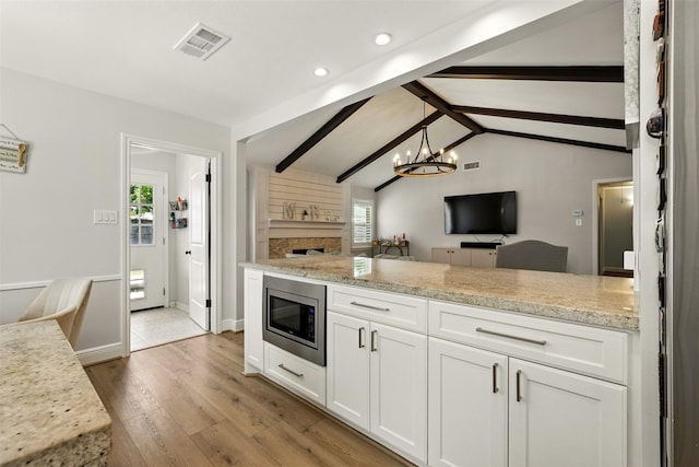 10718 Chevy Chase Dr, Houston, TX 77042 - kitchen with open floor plan, stainless steel microwave, wood finished floors, white cabinetry, and recessed lighting