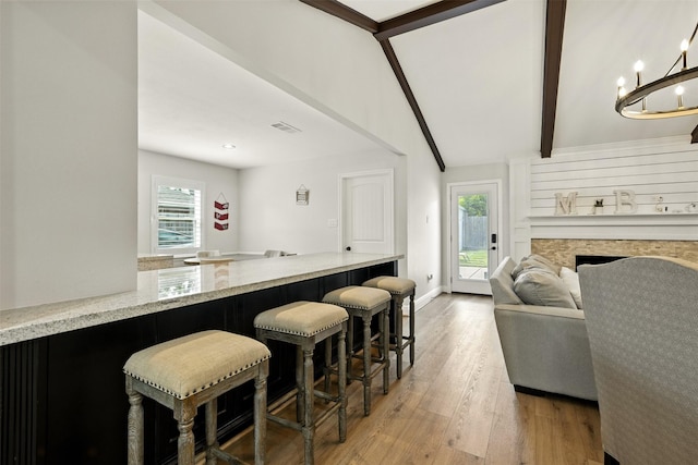 10718 Chevy Chase Dr, Houston, TX 77042 - kitchen with light stone counters, light wood-type flooring, open floor plan, a kitchen bar, and a fireplace