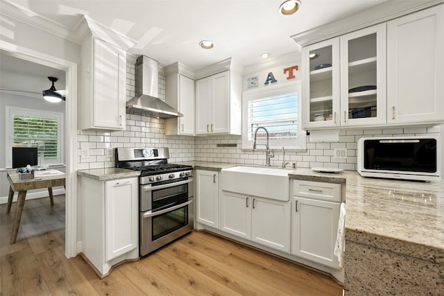 10718 Chevy Chase Dr, Houston, TX 77042 - kitchen featuring wall chimney range hood, range with two ovens, crown molding, white cabinets, and decorative backsplash