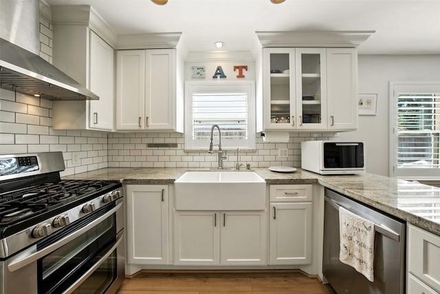 10718 Chevy Chase Dr, Houston, TX 77042 - kitchen with appliances with stainless steel finishes, wall chimney exhaust hood, white cabinets, and backsplash