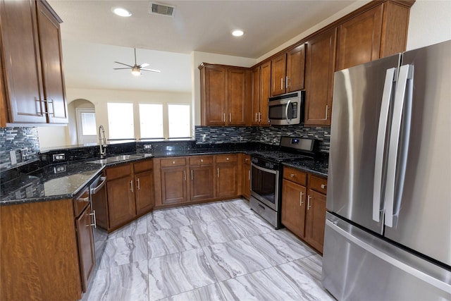6442 Wilshire Lks, Houston, TX 77040 - kitchen featuring stainless steel appliances, ceiling fan, dark stone countertops, arched walkways, and decorative backsplash