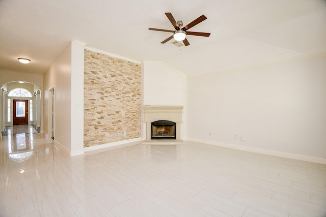 6402 Amelia Springs Dr, Spring, TX 77379 - unfurnished living room featuring arched walkways, ceiling fan, a fireplace with raised hearth, vaulted ceiling, and ornamental molding