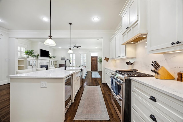 1136 Nadine St, Houston, TX 77009 - kitchen with range with two ovens, an island with sink, dark wood-style floors, a sink, and ornamental molding