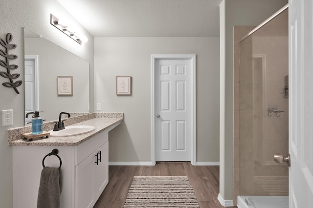 1887 Brushy Cedar Dr, Conroe, TX 77301 - bathroom featuring vanity, wood finished floors, tiled shower, and baseboards
