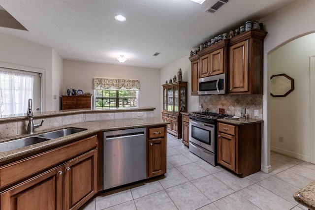 2312 W Green Briar Dr, Huntsville, TX 77340 - kitchen featuring stainless steel appliances, a sink, decorative backsplash, light tile patterned flooring, and light stone countertops