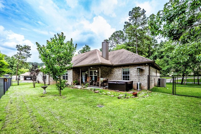 2312 W Green Briar Dr, Huntsville, TX 77340 - back of house featuring a hot tub, brick siding, central air condition unit, a patio area, and a chimney