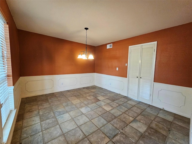 16438 Glenshannon Dr, Houston, TX 77059 - unfurnished dining area with a wainscoted wall, a chandelier, stone finish floors, and a decorative wall
