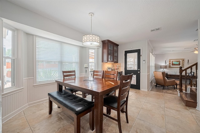 16418 Crawford St, Jersey Village, TX 77040 - dining room with light tile patterned floors, wainscoting, a ceiling fan, and a textured ceiling