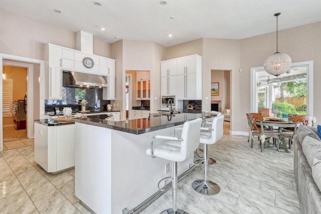 51 Wincrest Falls Dr, Cypress, TX 77429 - kitchen with dark countertops, extractor fan, backsplash, white cabinets, and a kitchen bar