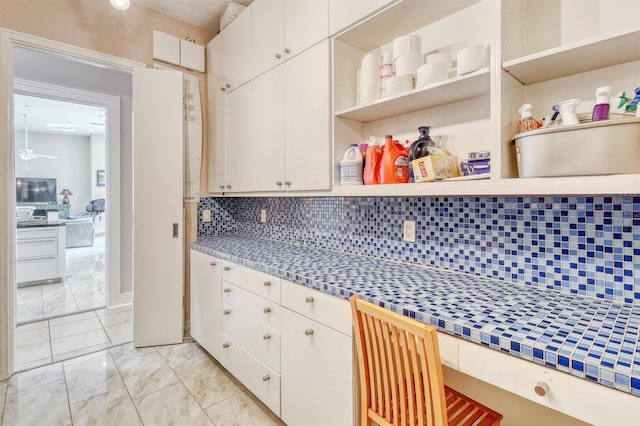 51 Wincrest Falls Dr, Cypress, TX 77429 - kitchen with open shelves, decorative backsplash, tile countertops, white cabinetry, and light marble finish floors