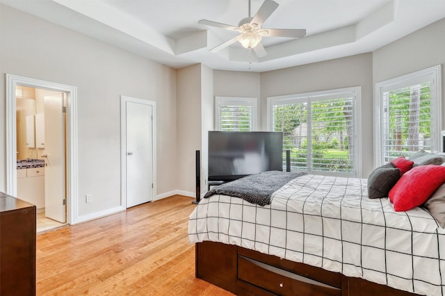 51 Wincrest Falls Dr, Cypress, TX 77429 - bedroom featuring multiple windows, light wood-type flooring, and a raised ceiling
