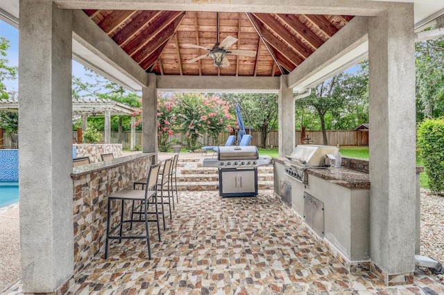 51 Wincrest Falls Dr, Cypress, TX 77429 - fenced backyard with a bar, an outdoor kitchen, a gazebo, a pergola, and ceiling fan