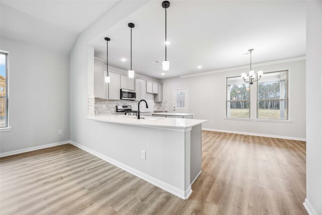 520 Barton Place Dr, Cleveland, TX 77327 - kitchen featuring appliances with stainless steel finishes, a sink, light countertops, a peninsula, and light wood-style floors