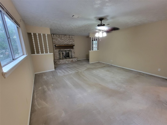 5211 Alamosa Ln, Spring, TX 77379 - unfurnished living room featuring a ceiling fan, healthy amount of natural light, a fireplace, carpet flooring, and a textured ceiling