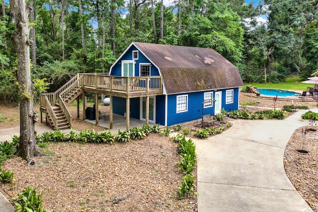 22827 Edward Ln, Tomball, TX 77377 - view of front of property featuring a deck, a gambrel roof, stairway, an outdoor pool, and a patio area