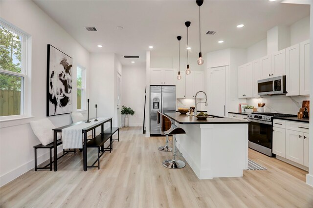 311 Marcella St Unit A, Houston, TX 77091 - kitchen featuring stainless steel appliances, a sink, dark countertops, light wood-type flooring, and plenty of natural light