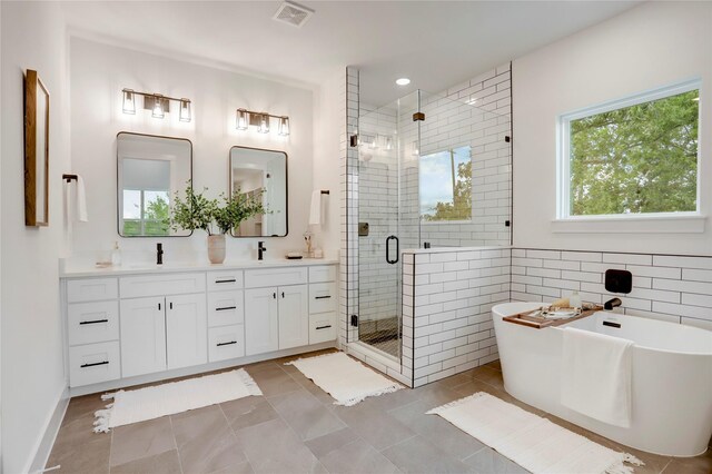311 Marcella St Unit A, Houston, TX 77091 - bathroom featuring a stall shower, double vanity, a freestanding bath, tile walls, and recessed lighting