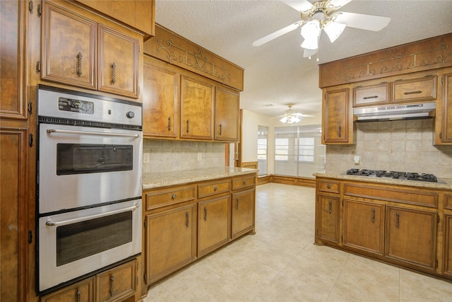 55 Flag Ct, Lake Jackson, TX 77566 - kitchen with stainless steel appliances, a ceiling fan, under cabinet range hood, brown cabinetry, and tasteful backsplash