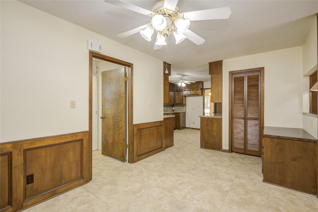 55 Flag Ct, Lake Jackson, TX 77566 - kitchen with a ceiling fan, brown cabinets, and a wainscoted wall