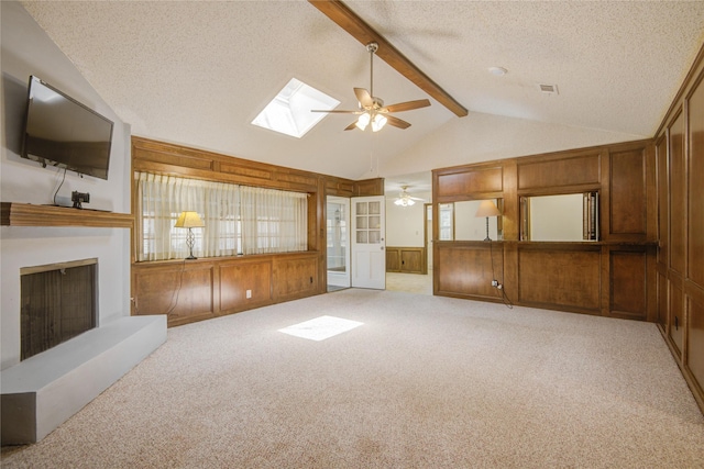 55 Flag Ct, Lake Jackson, TX 77566 - unfurnished living room featuring a ceiling fan, a textured ceiling, a fireplace with raised hearth, wooden walls, and carpet floors