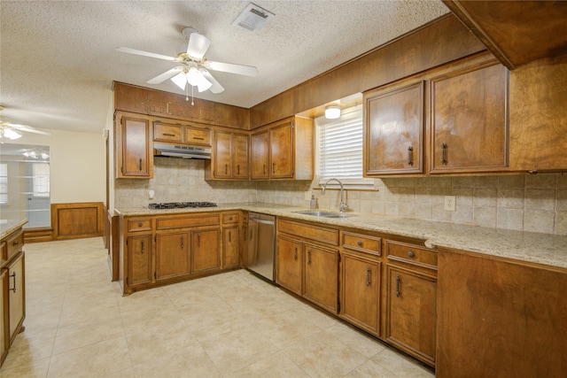 55 Flag Ct, Lake Jackson, TX 77566 - kitchen featuring stainless steel dishwasher, a ceiling fan, brown cabinets, under cabinet range hood, and gas stovetop
