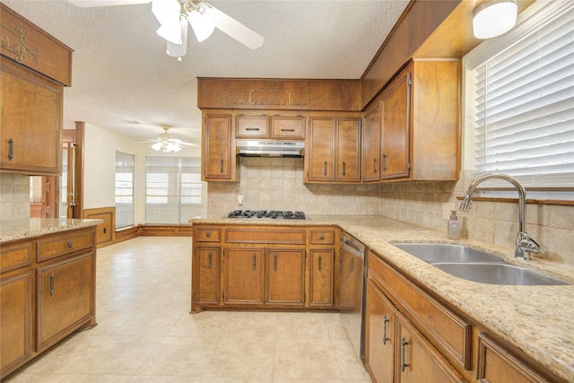 55 Flag Ct, Lake Jackson, TX 77566 - kitchen featuring a ceiling fan, a sink, under cabinet range hood, brown cabinetry, and stainless steel dishwasher
