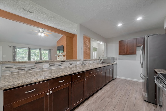 10534 Towne Square Rd, Sugar Land, TX 77498 - kitchen with stainless steel appliances, a ceiling fan, light stone counters, light wood-style flooring, and baseboards