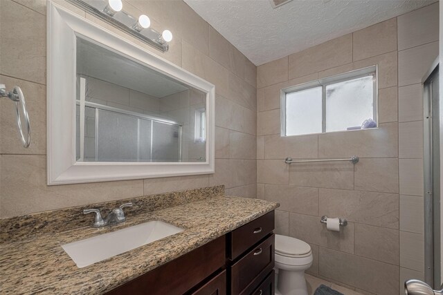 10534 Towne Square Rd, Sugar Land, TX 77498 - bathroom featuring vanity, a shower with door, tile walls, toilet, and a textured ceiling