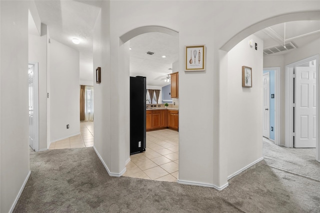 18206 Eton Ridge Ct, Richmond, TX 77407 - hallway with light colored carpet, arched walkways, light tile patterned flooring, baseboards, and recessed lighting