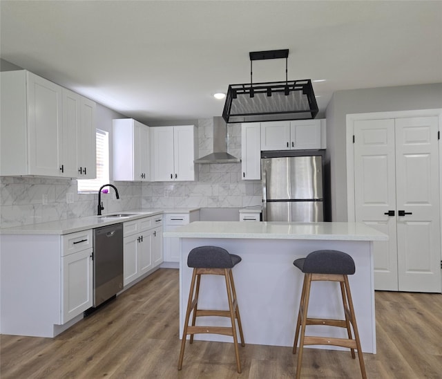 6502 Trail Valley Way, Houston, TX 77086 - kitchen with stainless steel appliances, wall chimney range hood, a breakfast bar, white cabinetry, and backsplash