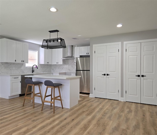 6502 Trail Valley Way, Houston, TX 77086 - kitchen featuring wall chimney range hood, appliances with stainless steel finishes, a center island, white cabinets, and a breakfast bar