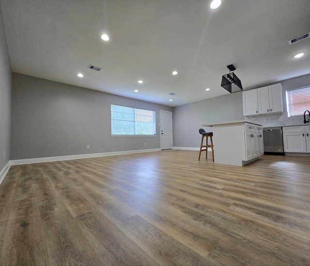 6502 Trail Valley Way, Houston, TX 77086 - kitchen featuring stainless steel dishwasher, open floor plan, white cabinets, baseboards, and light countertops