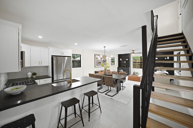 4813 Hummingbird St, Houston, TX 77035 - kitchen with stainless steel fridge, dark countertops, a peninsula, backsplash, and white cabinetry