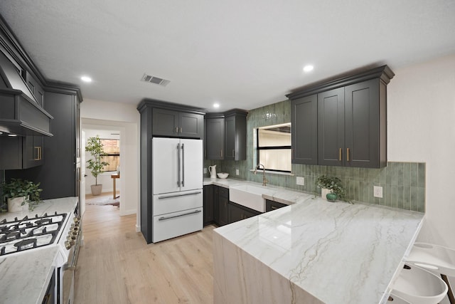 4813 Hummingbird St, Houston, TX 77035 - kitchen featuring white appliances, light wood-style floors, a peninsula, tasteful backsplash, and light stone countertops