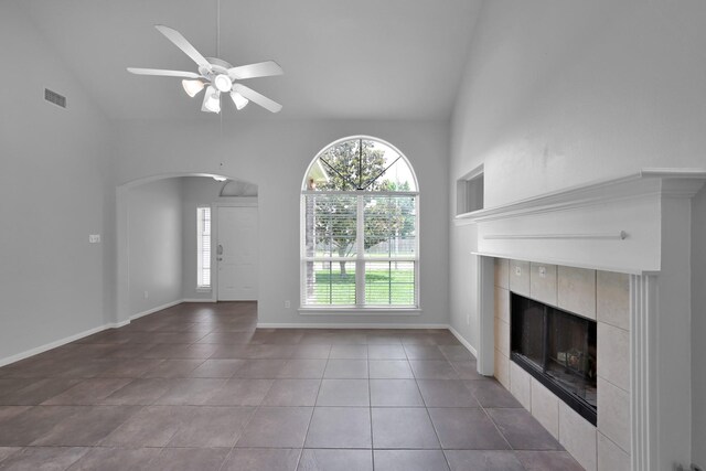 25819 Oakridge Forest Ln, Spring, TX 77386 - unfurnished living room with arched walkways, a fireplace, healthy amount of natural light, high vaulted ceiling, and tile patterned flooring