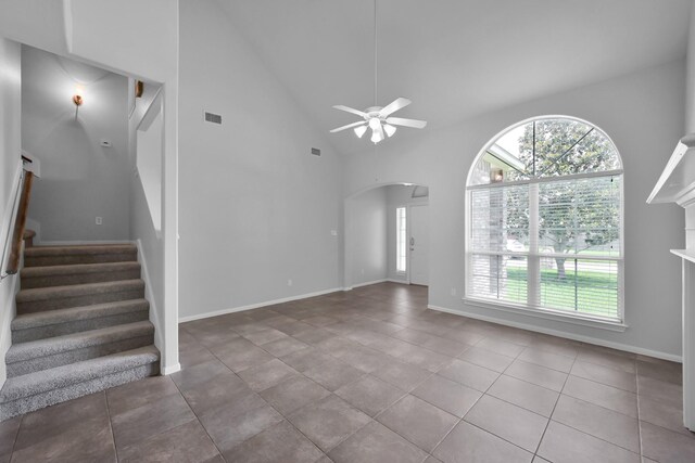 25819 Oakridge Forest Ln, Spring, TX 77386 - unfurnished living room with high vaulted ceiling, ceiling fan, stairway, tile patterned floors, and arched walkways