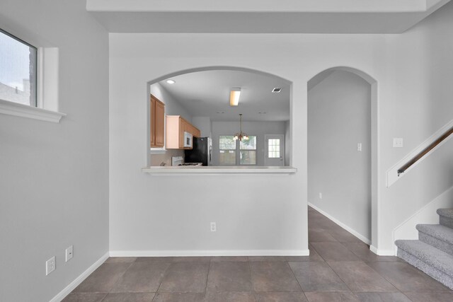 25819 Oakridge Forest Ln, Spring, TX 77386 - unfurnished living room featuring baseboards, dark tile patterned floors, stairway, and arched walkways