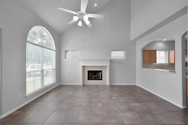 25819 Oakridge Forest Ln, Spring, TX 77386 - unfurnished living room with high vaulted ceiling, a ceiling fan, a tile fireplace, baseboards, and tile patterned floors
