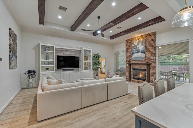 11 Hillsborough Dr E, Montgomery, TX 77356 - living area with ceiling fan, light wood-type flooring, a brick fireplace, beamed ceiling, and baseboards