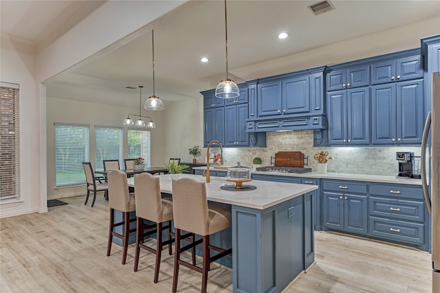 11 Hillsborough Dr E, Montgomery, TX 77356 - kitchen with blue cabinets, light wood-style flooring, a breakfast bar area, backsplash, and recessed lighting
